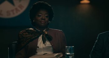 Movie still from “Air” (2023), directed by Ben Affleck – A woman sitting at a table with a glass of water in front of her; Medium shot, Over the shoulder angle