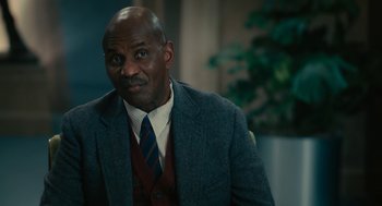 Movie still from “Air” (2023), directed by Ben Affleck – A man wearing a suit and tie in front of a plant; Close Up shot, Over the shoulder angle