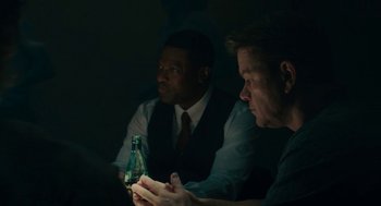 Movie still from “Air” (2023), directed by Ben Affleck – Two men sitting in a dark room looking at a phone; Medium shot, Over the shoulder angle