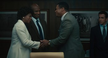 Movie still from “Air” (2023), directed by Ben Affleck – Two men and a woman shaking hands in a room; Medium shot, Over the shoulder angle