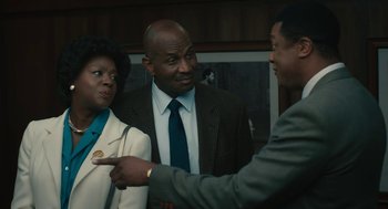 Movie still from “Air” (2023), directed by Ben Affleck – Two men and a woman in suits and ties talking to each other in a room; Medium shot, Over the shoulder angle