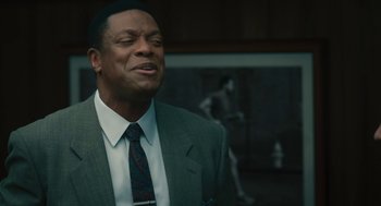Movie still from “Air” (2023), directed by Ben Affleck – A man in a gray suit and a red tie; Close Up shot, Over the shoulder angle