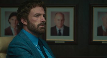 Movie still from “Air” (2023), directed by Ben Affleck – A man sitting in front of a picture of a man; Close Up shot, Over the shoulder angle