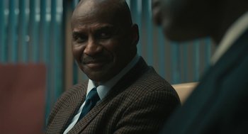 Movie still from “Air” (2023), directed by Ben Affleck – A man in a suit and tie sitting in a chair; Close Up shot, Over the shoulder angle