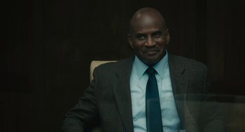 Movie still from “Air” (2023), directed by Ben Affleck – A man sitting in a chair wearing a suit and tie; Close Up shot, Over the shoulder angle