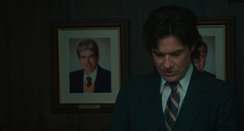 Movie still from “Air” (2023), directed by Ben Affleck – A man in a suit standing in front of a picture of himself; Close Up shot, Over the shoulder angle