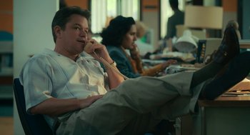 Movie still from “Air” (2023), directed by Ben Affleck – A man talking on a phone while sitting next to a woman; Medium shot, Low angle