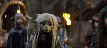 Movie still from “The Dark Crystal: Age of Resistance” (2019), created by Jim Henson – A person with a white wig and a mask on; Close Up shot, Over the shoulder angle