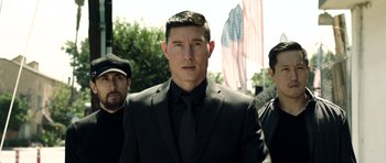 Movie still from “The Debt Collector” (2018), directed by Jesse V. Johnson – A man in a black suit and a black tie standing next to two other men; Close Up shot, Low angle