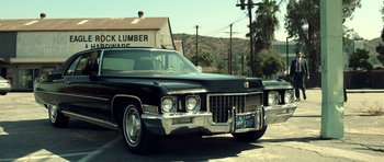 Movie still from “The Debt Collector” (2018), directed by Jesse V. Johnson – An old car parked in a parking lot near a building; Wide shot, Low angle