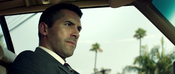 Movie still from “The Debt Collector” (2018), directed by Jesse V. Johnson – A person wearing a suit driving a car; Close Up shot, Low angle