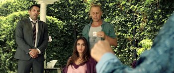 Movie still from “The Debt Collector” (2018), directed by Jesse V. Johnson – A woman sitting in front of a man in front of a hedge; Medium shot, Over the shoulder angle