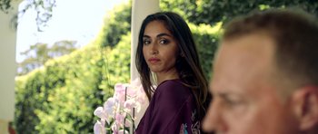 Movie still from “The Debt Collector” (2018), directed by Jesse V. Johnson – A beautiful woman in a purple shirt standing in front of flowers; Close Up shot, Over the shoulder angle