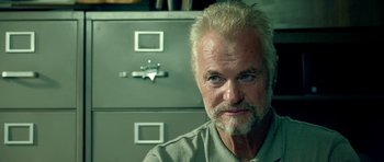 Movie still from “The Debt Collector” (2018), directed by Jesse V. Johnson – An older man sitting in front of a filing cabinet; Close Up shot, Low angle