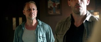 Movie still from “The Debt Collector” (2018), directed by Jesse V. Johnson – A man standing next to another man in front of a painting; Close Up shot, Over the shoulder angle