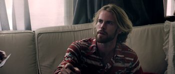 Movie still from “The Debt Collector” (2018), directed by Jesse V. Johnson – A man sitting on a couch looking at the camera; Close Up shot, Over the shoulder angle