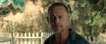 Movie still from “The Debt Collector” (2018), directed by Jesse V. Johnson – A person wearing a shirt near a fence; Close Up shot, Low angle