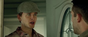 Movie still from “The Debt Collector” (2018), directed by Jesse V. Johnson – A young man wearing a hat and looking surprised; Close Up shot, Over the shoulder angle