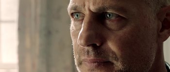 Movie still from “The Debt Collector” (2018), directed by Jesse V. Johnson – A man's face with blue - green eyes; Extreme Close Up shot, Low angle