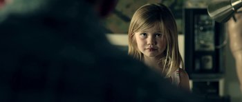 Movie still from “The Debt Collector” (2018), directed by Jesse V. Johnson – A little girl looking at the camera in a room; Close Up shot, Over the shoulder angle
