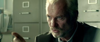 Movie still from “The Debt Collector” (2018), directed by Jesse V. Johnson – An older man with a gray beard and blue eyes looking at the camera; Close Up shot, Over the shoulder angle