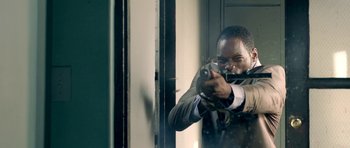 Movie still from “The Debt Collector” (2018), directed by Jesse V. Johnson – A man is holding a gun in a room; Close Up shot, Over the shoulder angle