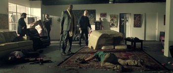 Movie still from “The Debt Collector” (2018), directed by Jesse V. Johnson – A group of people standing around a living room; Wide shot, Low angle