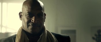 Movie still from “The Debt Collector” (2018), directed by Jesse V. Johnson – A bald man with a towel around his neck; Close Up shot, Low angle