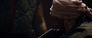 Movie still from “The Expendables” (2010), directed by Sylvester Stallone – A man in a turban is smoking a cigarette; Close Up shot, Over the shoulder angle