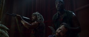 Movie still from “The Expendables” (2010), directed by Sylvester Stallone – A group of men standing next to each other holding guns; Medium shot, Low angle