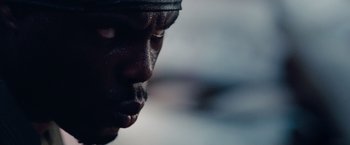 Movie still from “The Expendables” (2010), directed by Sylvester Stallone – A man's face with a black hat on; Extreme Close Up shot, Low angle