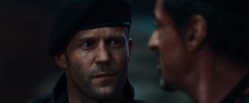 Movie still from “The Expendables” (2010), directed by Sylvester Stallone – A man in a black hat is looking at another man in a black hat; Close Up shot, Over the shoulder angle