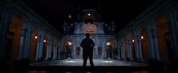 Movie still from “The Expendables” (2010), directed by Sylvester Stallone – A man standing in front of a building at night; Extreme Wide shot, Low angle