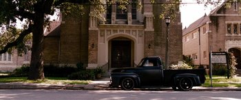 Movie still from “The Expendables” (2010), directed by Sylvester Stallone – An old truck parked on the side of the street; Extreme Wide shot, High angle