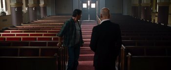Movie still from “The Expendables” (2010), directed by Sylvester Stallone – Two men are standing in a church with their backs turned to each other; Wide shot, High angle