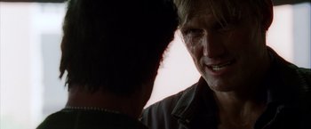 Movie still from “The Expendables” (2010), directed by Sylvester Stallone – A man is looking at another man in a dark room; Close Up shot, Over the shoulder angle