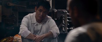 Movie still from “The Expendables” (2010), directed by Sylvester Stallone – A man sitting in front of another man in a room; Medium shot, Over the shoulder angle