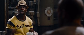 Movie still from “The Expendables” (2010), directed by Sylvester Stallone – A man sitting at a table holding a drink; Close Up shot, Over the shoulder angle