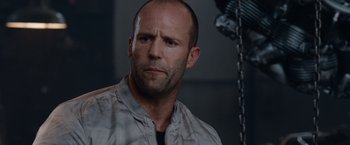 Movie still from “The Expendables” (2010), directed by Sylvester Stallone – A man with a bald head is looking at the camera; Close Up shot, Low angle