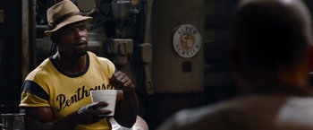 Movie still from “The Expendables” (2010), directed by Sylvester Stallone – A man sitting at a table with a cup of coffee; Close Up shot, Over the shoulder angle