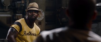 Movie still from “The Expendables” (2010), directed by Sylvester Stallone – A man wearing a hat looking at another man in a yellow shirt; Close Up shot, Over the shoulder angle