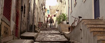 Movie still from “The Expendables” (2010), directed by Sylvester Stallone – Two people walking down a narrow alley way; Wide shot, Low angle