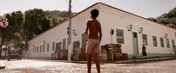 Movie still from “The Expendables” (2010), directed by Sylvester Stallone – A shirtless man standing in front of a white building; Wide shot, Low angle