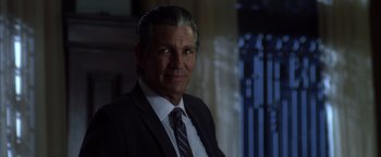 Movie still from “The Expendables” (2010), directed by Sylvester Stallone – A person wearing a suit and tie; Close Up shot, Over the shoulder angle