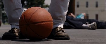 Movie still from “The Expendables” (2010), directed by Sylvester Stallone – A person standing next to a basketball on the ground; Extreme Close Up shot, Overhead angle