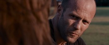 Movie still from “The Expendables” (2010), directed by Sylvester Stallone – A man's face in a field; Close Up shot, Over the shoulder angle