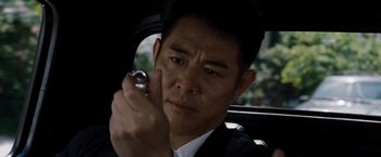 Movie still from “The Expendables” (2010), directed by Sylvester Stallone – A man in a car holding a cell phone to his ear; Close Up shot, High angle