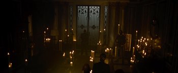 Movie still from “The Expendables” (2010), directed by Sylvester Stallone – A group of people standing around a room with candles; Wide shot, High angle
