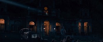 Movie still from “The Expendables” (2010), directed by Sylvester Stallone – People are gathered in front of a building at night; Extreme Wide shot, Low angle