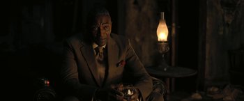 Movie still from “The Fall of the House of Usher” (2023), directed by Mike Flanagan – An older man sitting in a chair holding a cell phone; Medium shot, Over the shoulder angle